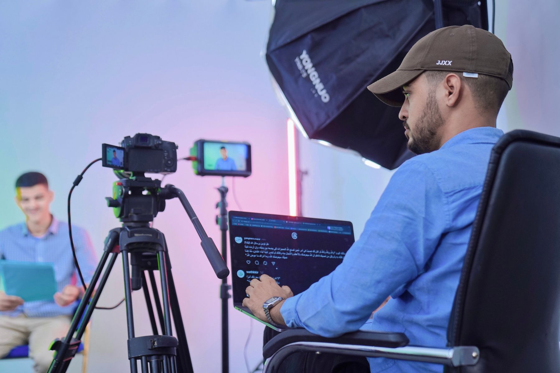 A video producer filming a presenter in a studio.